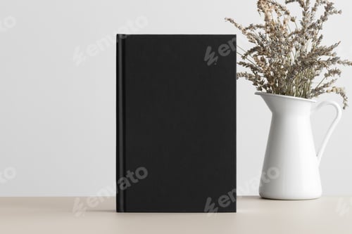 Preview: Black book mockup with a lavender decoration on a beige table.