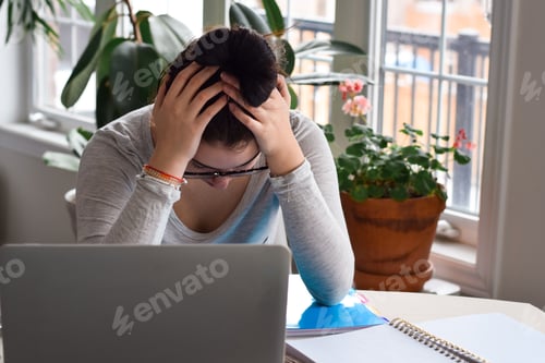 Preview: Young girl student sitting at desk stressed tired and frustrated while studying online