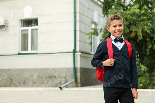 Preview: Boy with backpack against school building, space for text