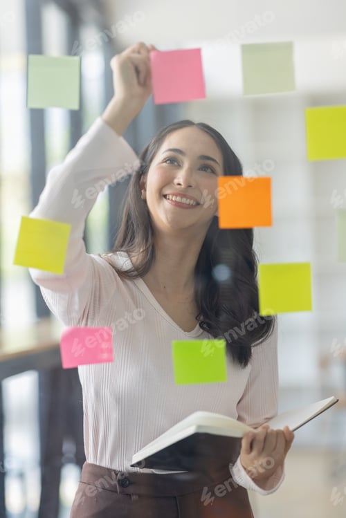 Preview: Business female employee with many conflicting priorities arranging sticky notes commenting and brai