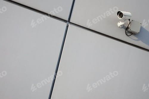 Preview: White surveillance camera built into the metal wall of the office building