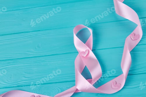 Preview: Pink ribbon tape on blue wooden desk.