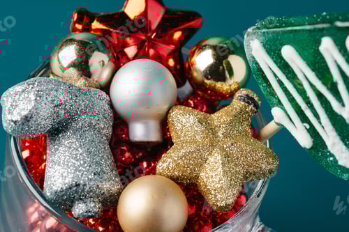 Preview: Glass with Christmas decorations on dark green background