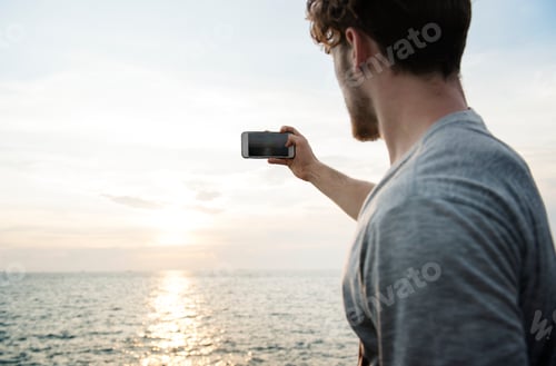 Preview: Caucasian man taking a photo of the sunset