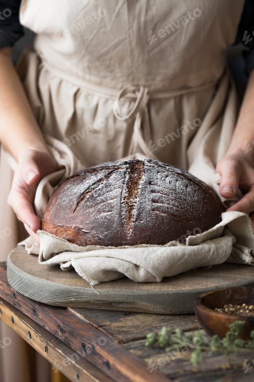 Preview: Woman baker's holding hot sourdough bread closeup
