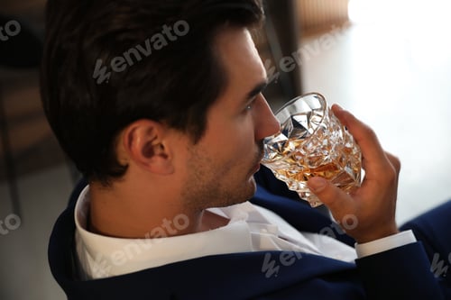 Preview: Young man with glass of whiskey indoors