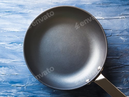 Preview: Empty frying pan on blue background.