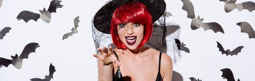 Preview: panoramic shot of girl in black witch Halloween costume with red hair near white wall with