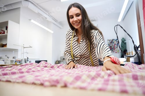 Preview: Smiling designer lays out plaid fabric on cutting table