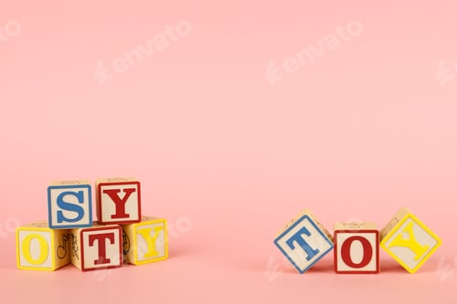 Preview: Pink background and toy colored cubes with letters