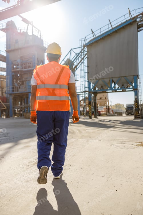 Preview: Young worker dressed in safety equipment inside factory