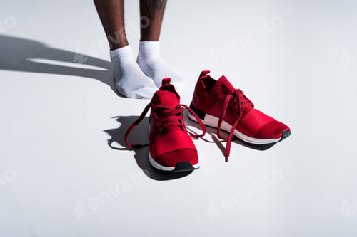 Preview: close-up partial view of sportsman in socks and red sports shoes on grey