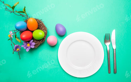 Preview: Easter table, place setting. Easter eggs, empty white plate, green background