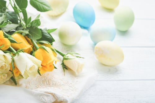 Preview: Happy Easter. Easter eggs on rustic table with white and yellow roses. Natural dyed colorful eggs in