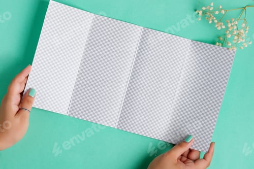 Preview: Four-fold brochure mockup in a hand above aquamarine background