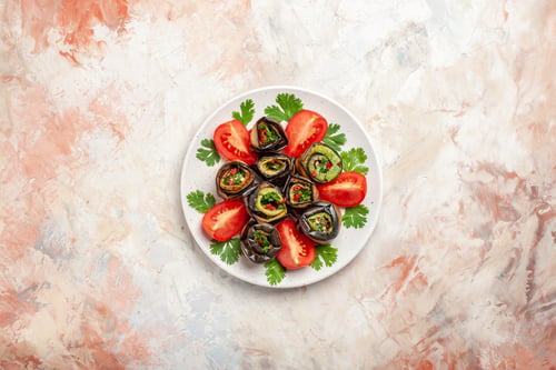 Preview: top view delicious eggplant rolls with greens and tomatoes on a light background food dish photo