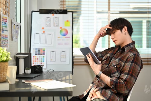 Preview: Focused male UX designer using digital tablet working on mobile app interface wireframe design.