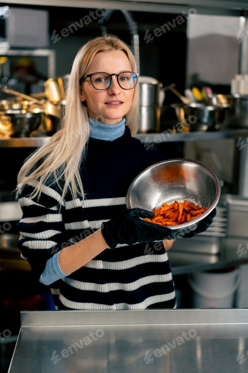 Preview: girl with glasses in kitchen stands with a bowl of sweet potato demonstrating looking at the camera