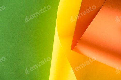 Preview: close-up shot of rolled yellow and orange papers on green background