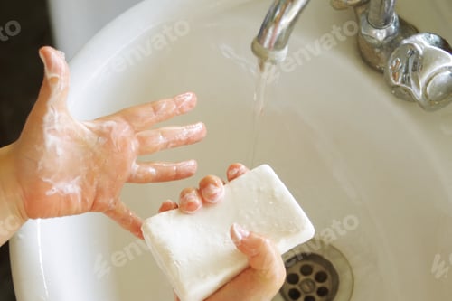 Preview: a child washes his hands with soap under a stream of clean water in the bathroom