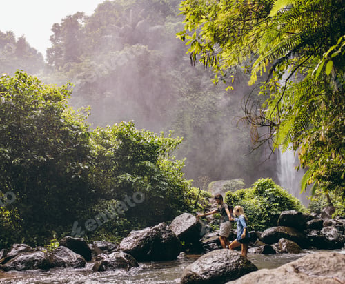 Preview: Couple crossing a stream on hike in forest