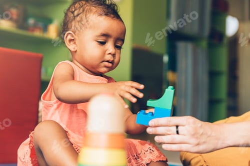 Preview: Happy baby playing with toy blocks.