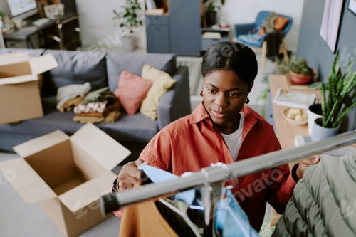 Preview: Black Adult Woman Sorting Clothes While Moving into New Home