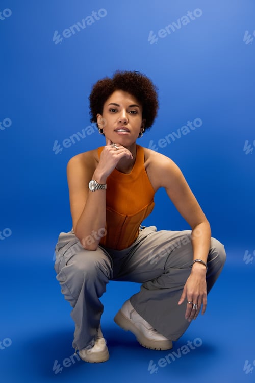 Preview: Stylish young woman exudes elegance in vibrant blue background with confident pose
