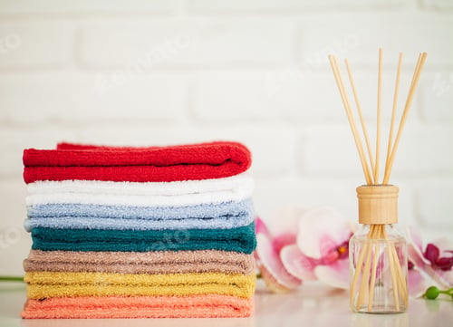 Preview: Fluffy bath towels on light wooden table with aroma sticks