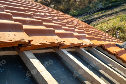Preview: Overlapping rows of yellow ceramic roofing tiles mounted on wooden boards covering residential