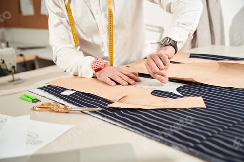 Preview: Experienced tailor preparing to cut fabric in atelier
