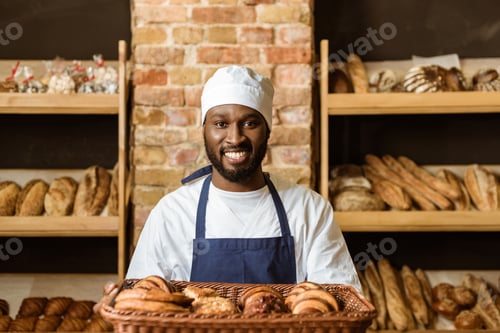 Preview: smiling african american baker holding basket with sweet pastry