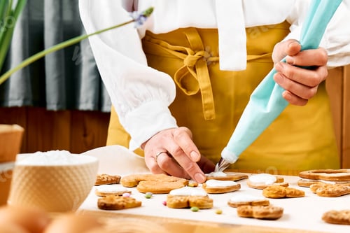Preview: Woman decorating heart shaped cookies with frosting.