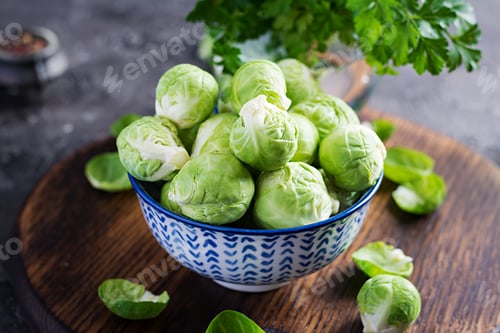 Preview: Fresh organic brussels sprouts in a bowl on a dark background. Healthy food. Vegan/vegetarian meal.