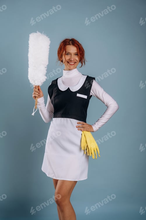 Preview: White dust brush in hand, professional maid. Woman is in the studio against background