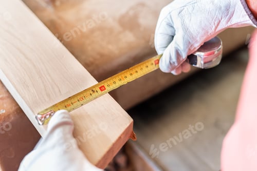 Preview: Person measuring a wooden plank with a meter