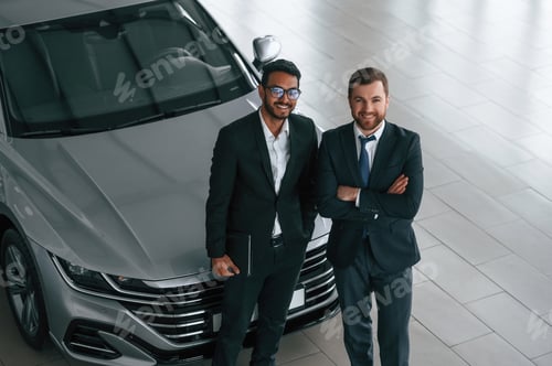 Preview: View from the top. Two businessmen are working together in the car showroom