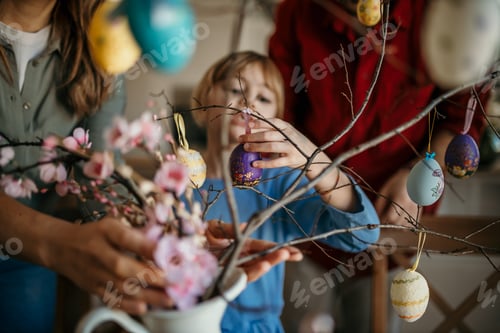 Preview: Child decorating spring tree branches with easter eggs