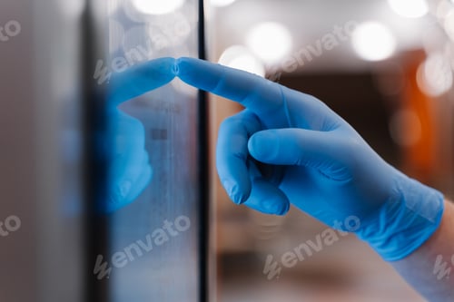 Preview: Mans hand in latex medical glove, uses touchscreen, checks information during quarantine