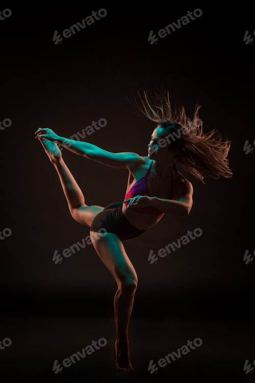 Preview: Young beautiful dancer in beige dress dancing on black background