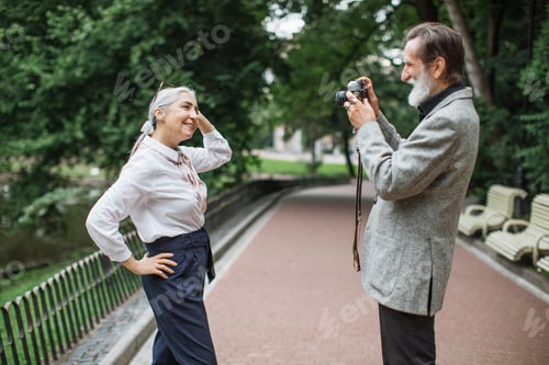 Visualização: Homem idoso sorridente tirando foto de uma linda esposa na câmera retrô