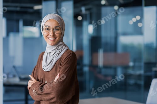 Preview: An Arab business woman in hijab. Standing in the office, looking at the camera, crossed her arms