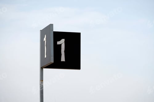 Preview: Closeup of a black outdoor sign with number one against a sky