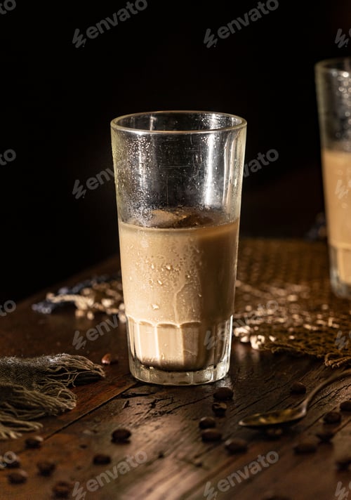 Preview: Vertical shot of ice coffee in a glass cup on wooden table