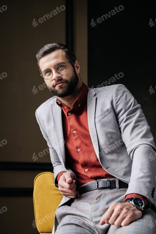 Preview: handsome stylish elegant man in glasses and suit sitting on couch
