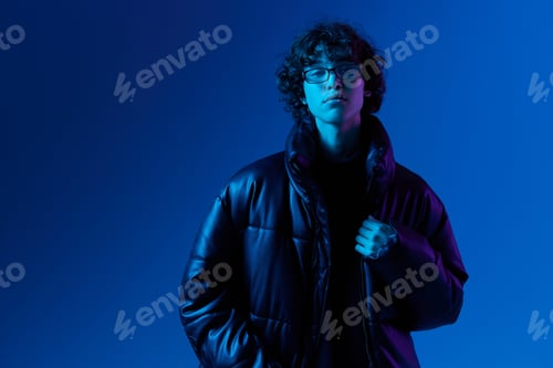Preview: Man in winter down jacket model posing with glasses, hipster lifestyle, portrait blue background