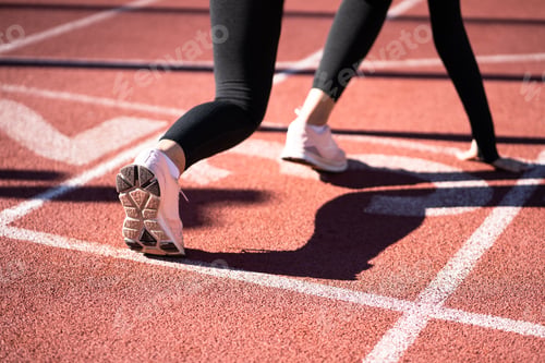 Preview: Rear view of woman jogger on running track getting ready to start run.