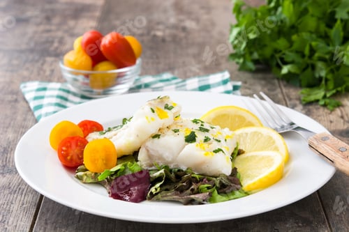 Preview: Delicious steamed cod fillet with lemon and cherry tomatoes on a wooden table