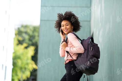Preview: Beautiful young African woman walking with bag outside and talking on phone