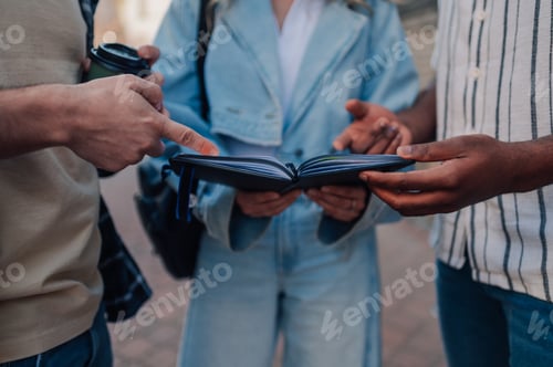 Preview: Students reading and discussing notes in a notebook outdoors